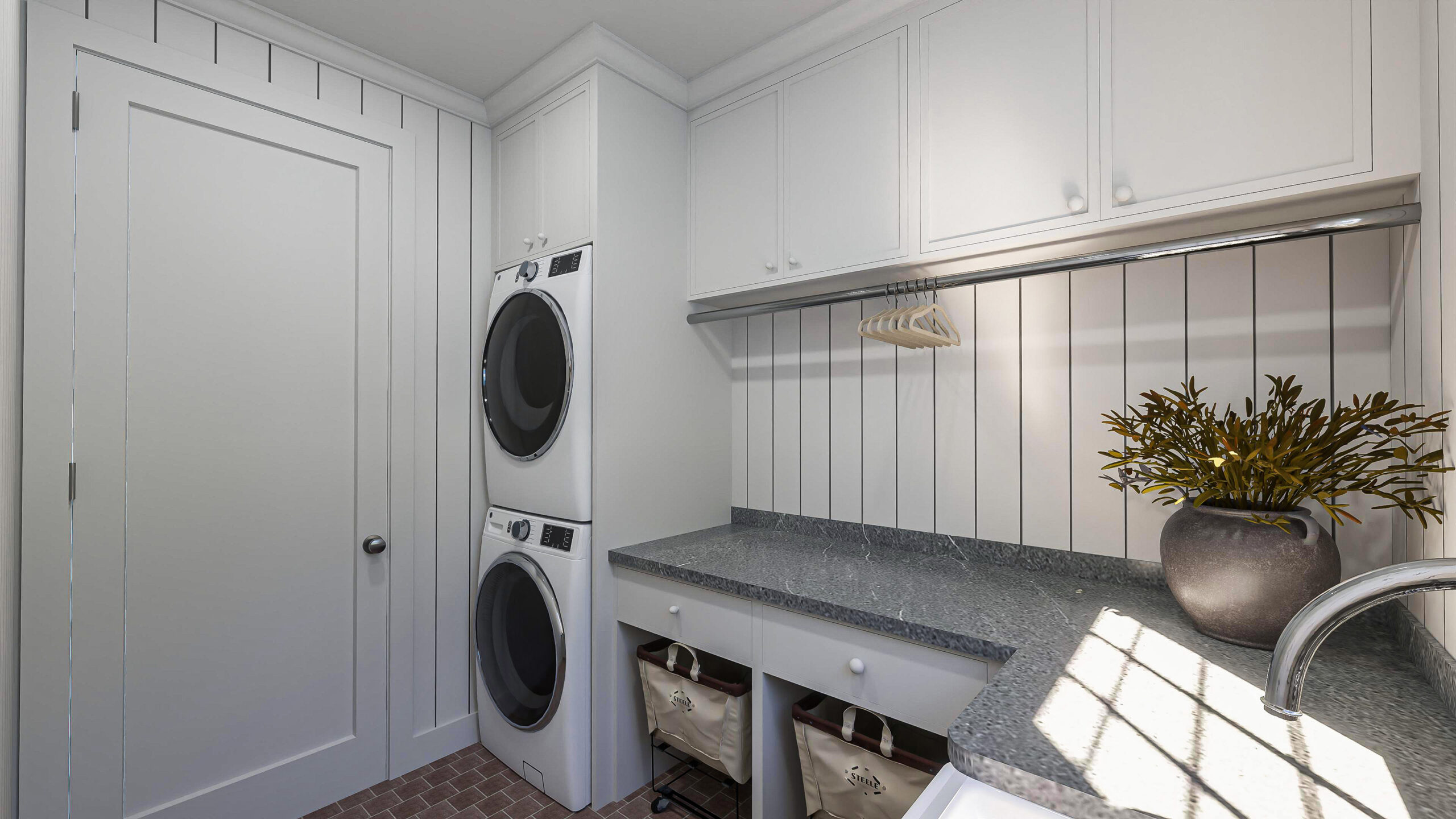 Custom new build laundry room with slim shaker cabinetry, stacked washer and dryer, and a long soapstone folding counter