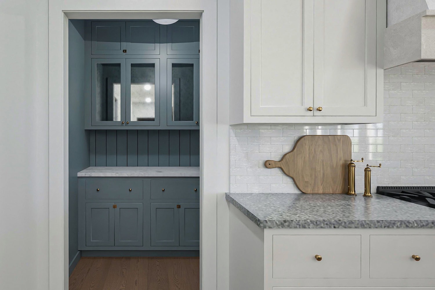 A look into a dark blue pantry with marble countertops.