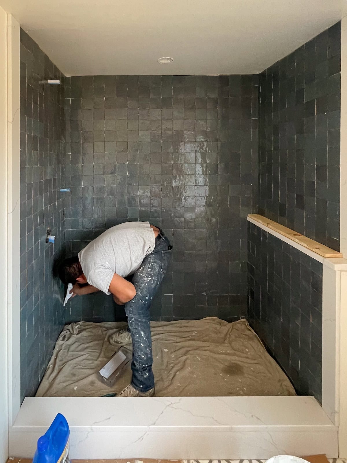 A tile contractor grouting zellige tiles in a custom shower.
