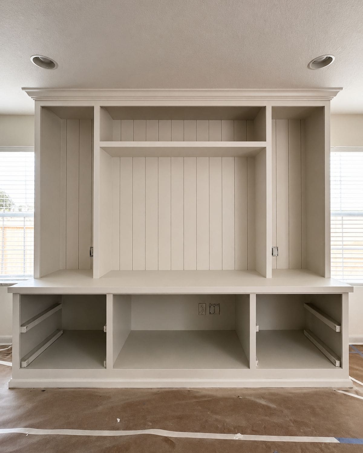 Painted entertainment center built-ins showing the original base cabinetry integrated with new upper millwork and tongue-and-groove paneling.