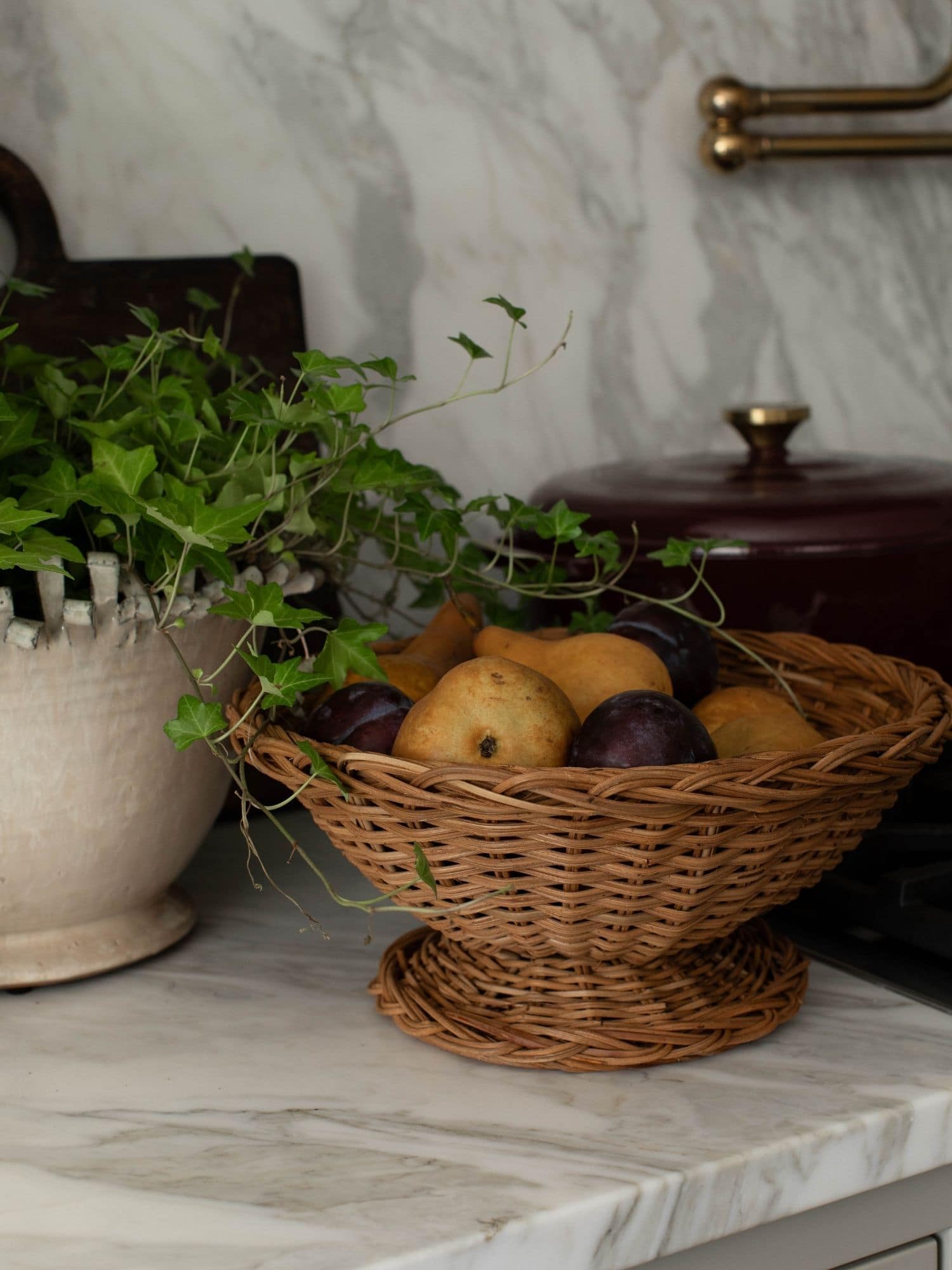 Styled kitchen countertop with a woven fruit basket and greenery during the installation phase of a full-service interior design project.