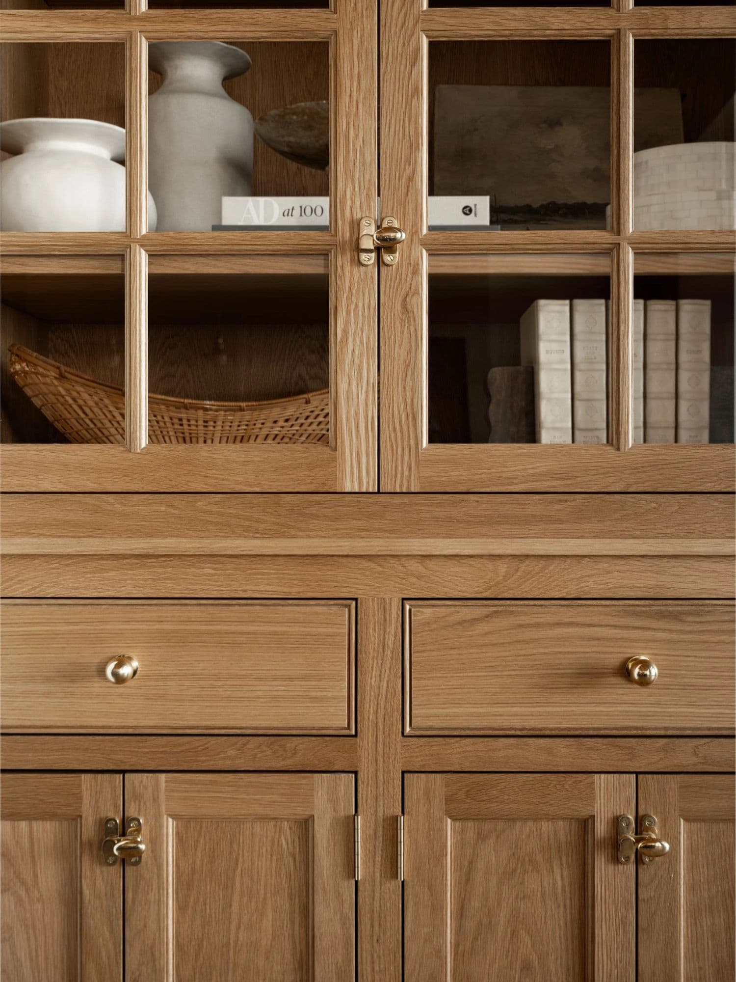 Natural wood cabinetry with visible grain, glass doors, and brass hardware.